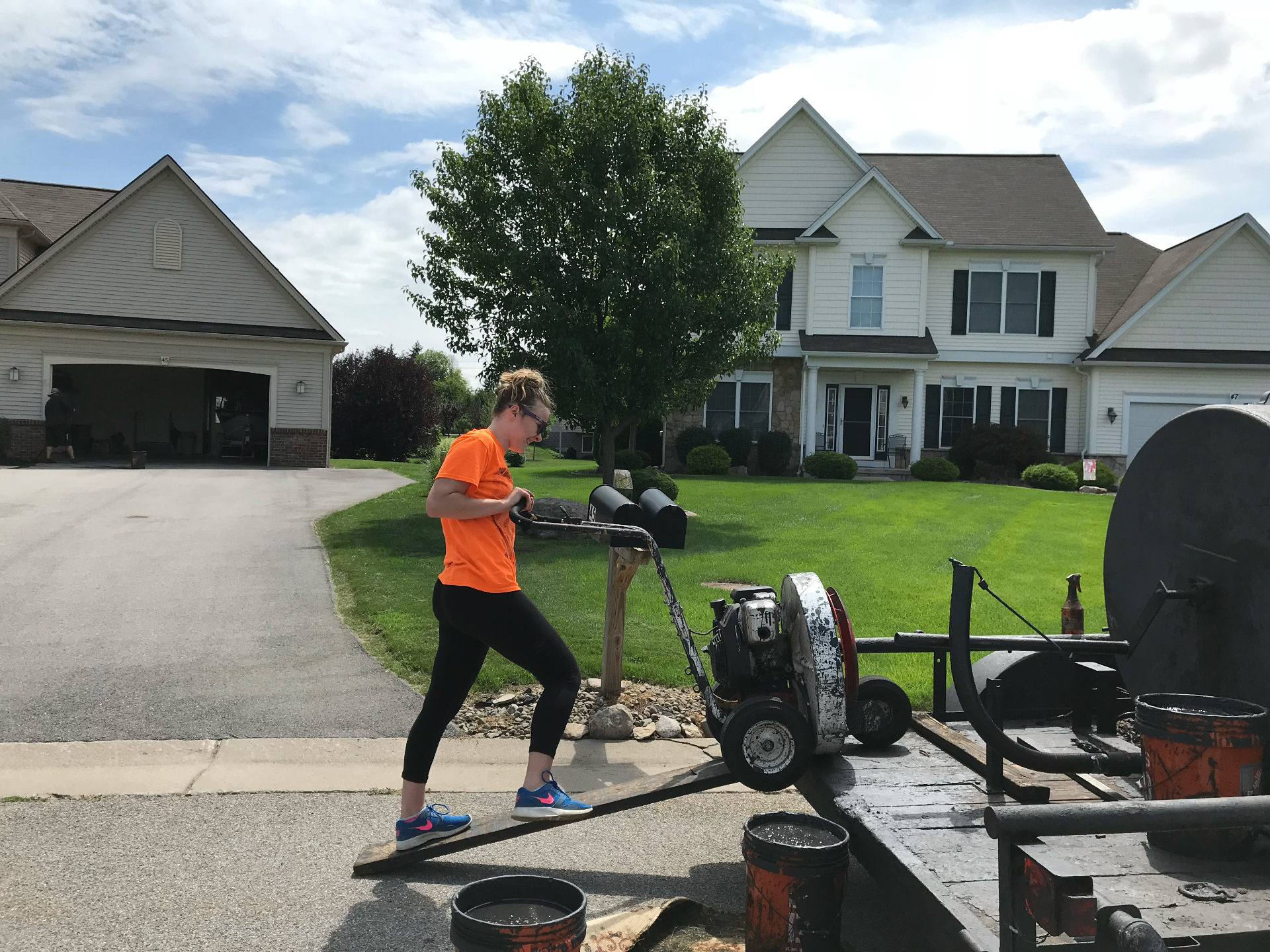 Christina loading sealcoating equipment off the trailer at a suburban Rochester home